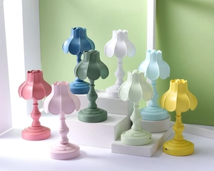 Dettaglio di mini lampade da notte LED a forma di fiore in vari colori su supporto bianco