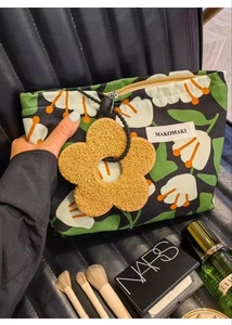 Detailed shot of tropical leaf canvas makeup bag with large yellow flower charm