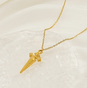 Detailed close-up of a 18K gold plated cross dagger pendant on a fine link chain necklace