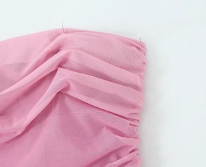 Dettaglio del tessuto a rete rosa con trama fine e design a strati arricciati per abiti da donna