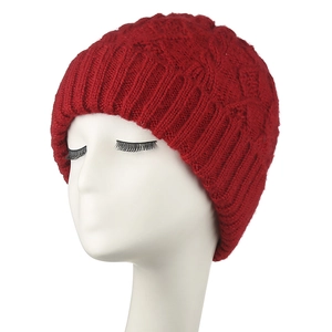 Close-up of red cable knit beanie showing thick wool blend texture and ribbed cuff details