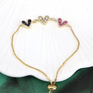 Detail of adjustable gold chain bracelet with three colorful zircon heart charms