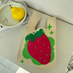 Close-up of beige knitted tote bag featuring a vibrant red strawberry pattern and texture