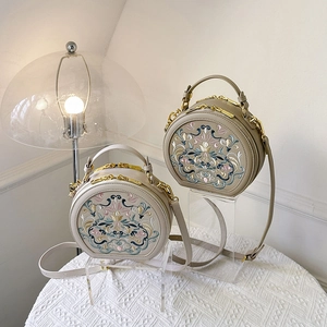 Detail of two beige round shoulder bags featuring intricate ethnic floral embroidery