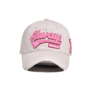 Macro view of distressed brim and 3D pink letter embroidery on beige cotton baseball cap