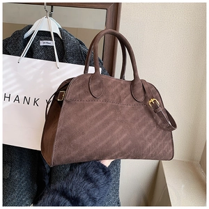Detail of dark brown matte leather tote bag with dual handles and gold hardware