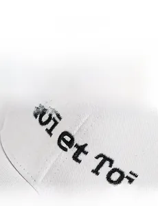Macro detail of Moi et Toi embroidery on a white cotton twill baseball cap with black thread