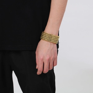 Close-up of a wide gold-plated stainless steel fish scale chain bracelet worn by a model