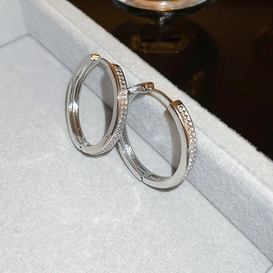 Close-up of silver geometric hoop earrings with sparkling zircon stones in a jewelry box