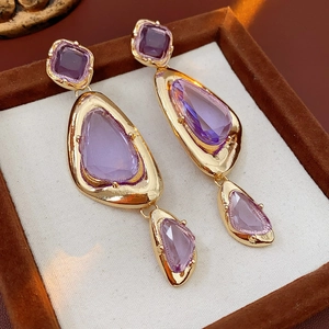 Macro detail of vintage gold earrings with purple crystal tassels in a luxury jewelry box
