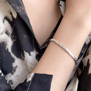 Minimalist S925 sterling silver twisted open bangle bracelet shown on a female wrist