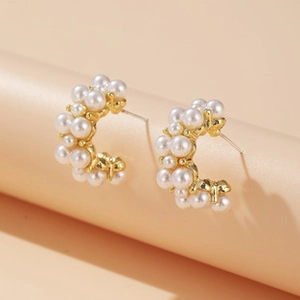 Detail of elegant gold-tone C-shaped hoop earrings with cluster white pearls