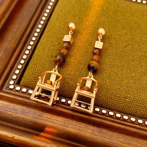 Detail of vintage gold chair earrings with brown beads on green textured fabric