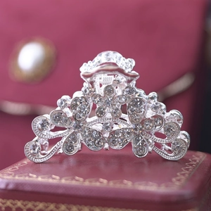 Close-up of a silver floral hair claw with crystals on a luxury red jewelry box