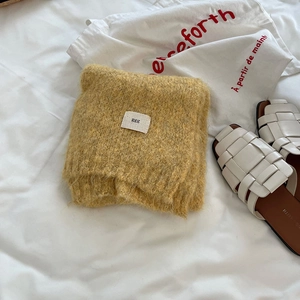 Detail of soft yellow wool scarf showing plush texture and minimalist woven label