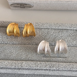 Minimalist brushed metal C-shaped earrings in gold and silver set on velvet tray