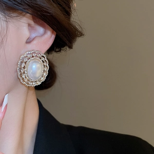 Detail of French-style gold earring with oval pearl and zircon filigree on model