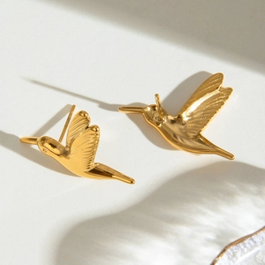 Detailed view of polished golden hummingbird stud earrings with elegant light and shadow