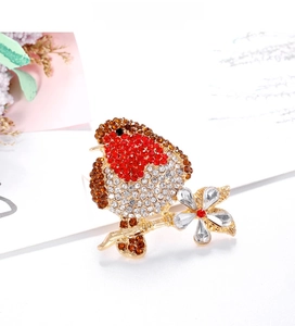 Macro shot of an elegant bird brooch with red rhinestones perched on a golden flower branch