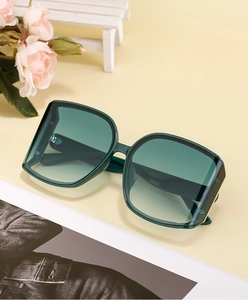 Detail of dark green oversized sunglasses with gradient lenses and gold metal accents