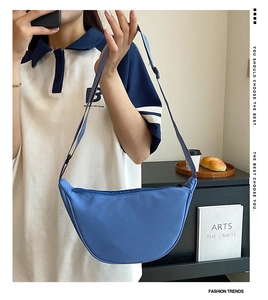Side view of a light blue nylon crescent bag worn by a model in a lifestyle setting
