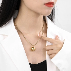 Close-up of golden snake chain necklace featuring a polished spherical ball pendant