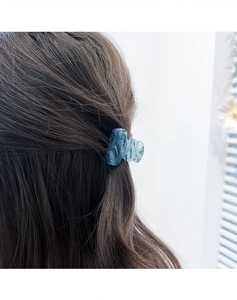 Close-up of a blue marble texture hair claw clip worn on a side hairstyle