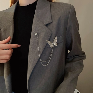Detailed close-up of a silver butterfly chain brooch pinned on a grey blazer