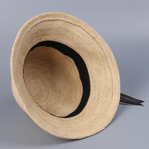 Detailed view of handmade raffia bucket hat featuring a black ribbon bow and textured weave