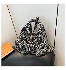 Close-up of black and white leopard print backpack featuring metal ring and multi-pocket detail