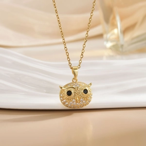 Close-up of golden owl pendant with sparkling crystals and black stone eyes on a chain