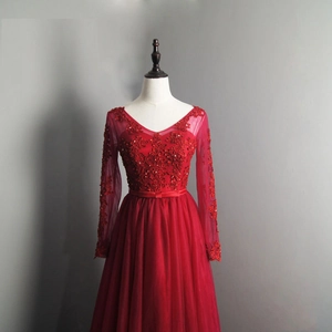 Detail of red evening gown featuring V-neck lace bodice with sequins and sheer mesh sleeves