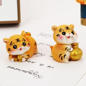 Close-up of two cute tiger figurines holding a gold coin and a money bag for decor