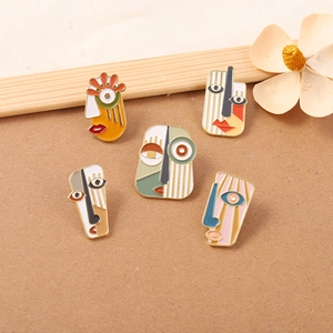 Detailed macro view of five abstract artistic face brooches with colorful enamel finish
