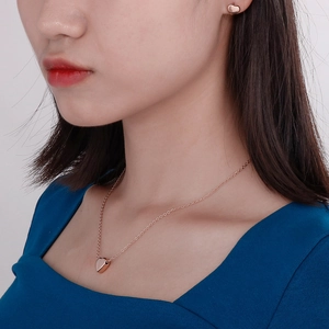 Dettaglio del set collana e orecchini a cuore in oro rosa 14k indossato da una modella