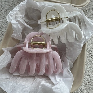 Detail of pink and white marble texture hair claws with gold springs in a gift box