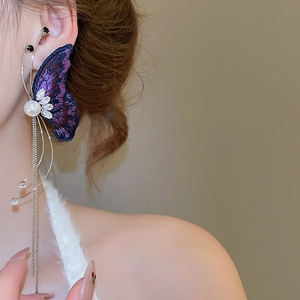 Detail of purple embroidered butterfly earrings with white pearls and silver tassel chains
