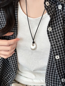 Minimalist silver teardrop pendant necklace with black cord shown on a female model
