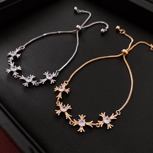 Detailed close-up of gold and silver cross bracelets with zircon stones on a black tray
