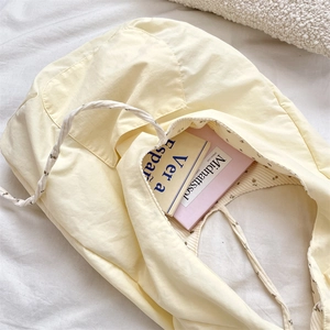 Detail of spacious cream corduroy tote bag interior with books on soft white bedding