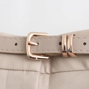 Detail of beige faux leather belt with golden square buckle on matching casual shorts