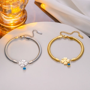 Detail of gold and silver snake bone bracelets with clover and blue evil eye charms