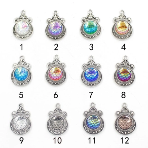 Macro shot of twelve assorted 12mm mermaid fish scale pendants with antique silver base