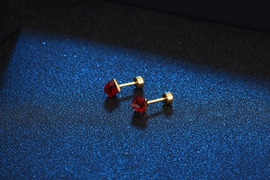 Detailed close-up of square red crystal stud earrings with golden screw back design