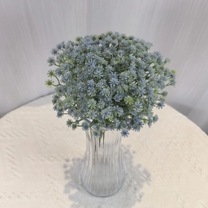 Close-up of blue artificial babys breath flowers in a vertical striped glass vase