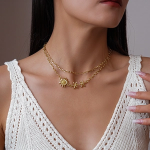 Détail du collier doré à double rangée avec pendentifs soleil et étoiles sur la peau