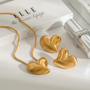 Golden titanium steel heart necklace and stud earrings jewelry set on a clean background