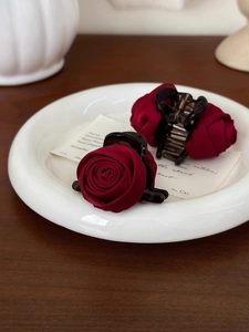 Detailed macro view of two deep red silk rose hair claws on a ceramic plate
