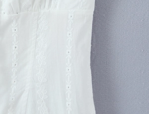 Macro shot of white lace embroidery detail and hollowed-out fabric on a cotton dress