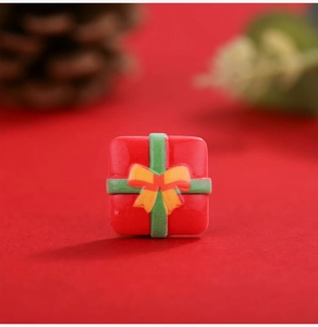 Macro view of miniature red resin gift box charm with green ribbon for DIY crafts